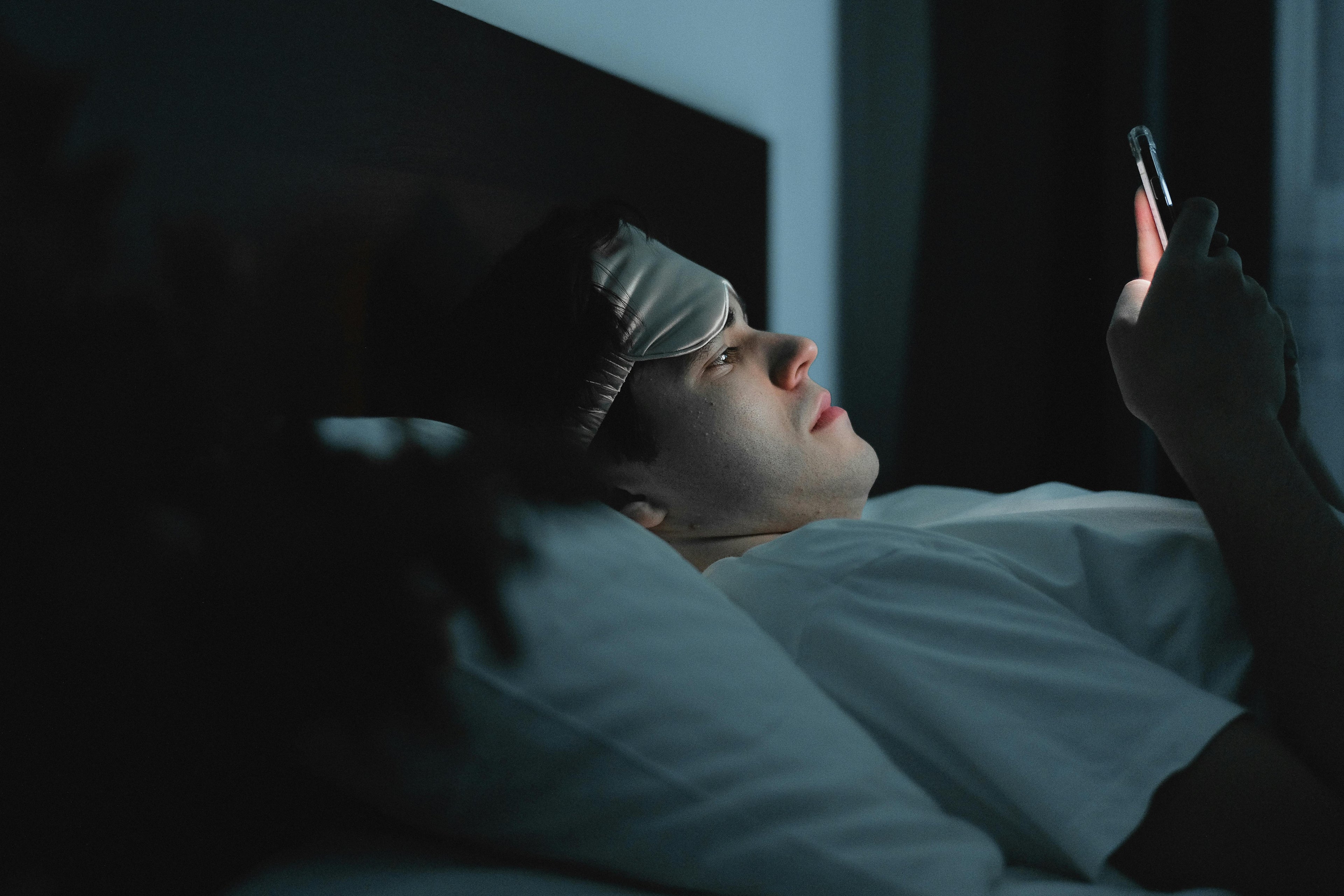 Man laying in bed late at night on his phone